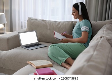 Young Woman Watching Webinar On Sofa At Home