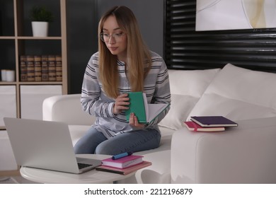 Young Woman Watching Webinar On Sofa At Home