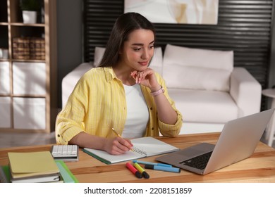 Young Woman Watching Webinar At Table In Room