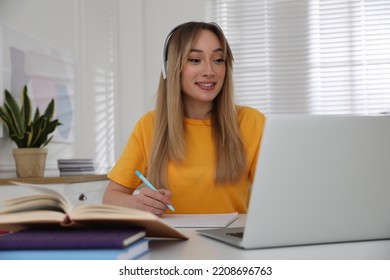 Young Woman Watching Webinar At Table In Room