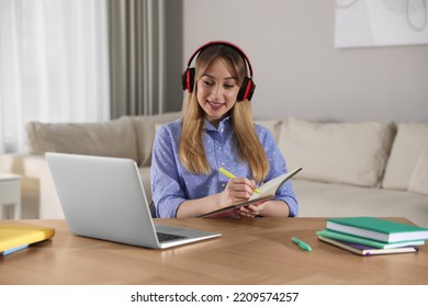 Young Woman Watching Webinar At Table In Room