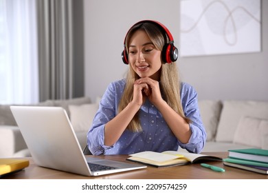 Young Woman Watching Webinar At Table In Room