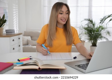 Young Woman Watching Webinar At Table In Room