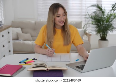 Young Woman Watching Webinar At Table In Room