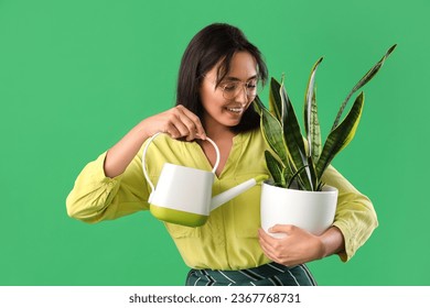 Young woman watering plant on green background - Powered by Shutterstock