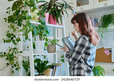 Young woman watering pots with plants from watering can, home interior - Powered by Shutterstock