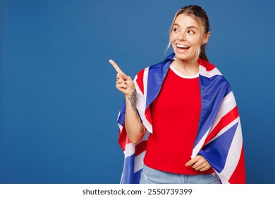 Young woman wear basic red t-shirt hat wrapped in British flag cheer up support football sport team hold in hand soccer ball watch tv live stream point finger aside isolated on plain blue background - Powered by Shutterstock