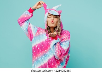 Young woman wear domestic costume with hoody hold animals ears sending blow air kiss look camera invite for pajama party isolated on plain pastel light blue cyan background. People lifestyle concept