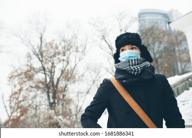 Young Woman Wear Face Mask For Sickness Coronavirus Protection. Low View Of Female Human Wear Warm Clothes Outside In Winter Time. Get Ready For Infection Hazzard Or Sickness On Streets