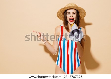 Young woman wear one-piece swimsuit straw hat near hotel pool scream in megaphone announce sale Hurry up point aside on area isolated on plain beige background Summer vacation sea rest sun tan concept