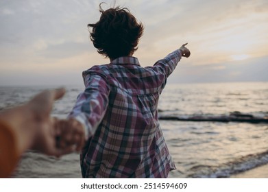 Young woman wear shirt casual clothes walk hold boyfriend hand say follow me point finger on sky horizon rest on sea ocean sand shore beach outdoor seaside in summer day free time. Lifestyle concept - Powered by Shutterstock