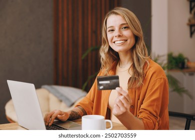 Young woman wear shirt use laptop pc computer hold credit bank card shopping online sitting alone at table in coffee shop cafe relax rest at restaurant inside. Freelance mobile office business concept - Powered by Shutterstock