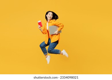 Young woman wear summer clothes jump with passport ticket laptop pc computer isolated on plain yellow background. Tourist travel abroad in free spare time rest getaway. Air flight trip journey concept