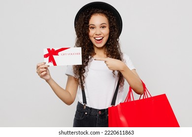 Young Woman Wear T-shirt Hat Hold In Hand Red Paper Package Bags After Shopping Show Store Gift Coupon Voucher Card Isolated On Plain Solid White Background Studio. Black Friday Sale Buy Day Concept