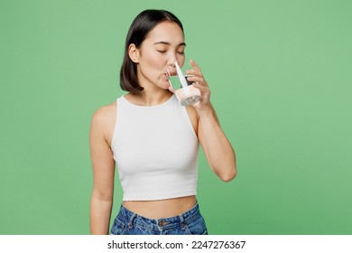 Young woman wear white clothes hold transparent glass drink clear fresh pure still water close eyes isolated on plain pastel light green background. Proper nutrition healthy fast food choice concept