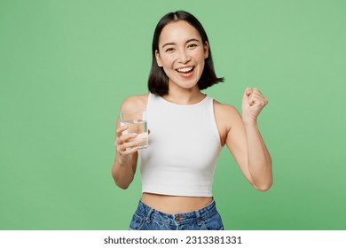Young woman wear white clothes hold drink clear fresh pure still water from glass do winner gesture isolated on plain pastel light green background. Proper nutrition healthy fast food choice concept
