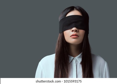 young woman wearing black blindfold isolated on grey