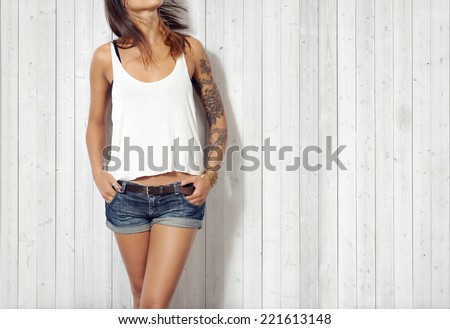 Young woman wearing blank vest. Wood wall background.
