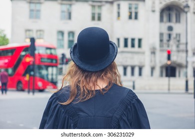 A Young Woman Wearing A Bowler Hat And A Graduation Gown Is Walking The Streets Of London