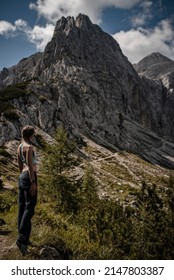 Young woman wearing braids is enjoying beautiful view of both Mala and Velika Mojstrovka in Slovenia during a late summer hike in Julian Alps