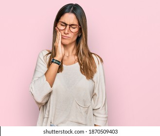 Young woman wearing casual clothes and glasses touching mouth with hand with painful expression because of toothache or dental illness on teeth. dentist 