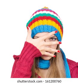 Young woman wearing colorful hat hiding behind her hand