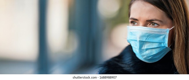 Young woman wearing disposable blue virus face mouth nose mask, closeup portrait - wide banner with space for text left side. Coronavirus covid-19 outbreak prevention concept