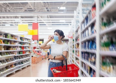 Young woman wearing disposable medical mask shopping in supermarket during coronavirus pneumonia outbreak. 