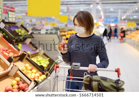 Young woman wearing disposable medical mask shopping in supermarket during coronavirus pneumonia outbreak. Protection and prevent measures while epidemic time.