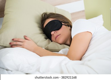 Junge Frauen tragen Augenmaske beim Schlafen im Bett