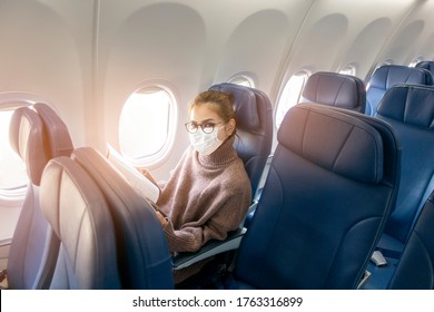 A Young Woman Wearing Face Mask Is Traveling On Airplane , New Normal Travel After Covid-19 Pandemic Concept 