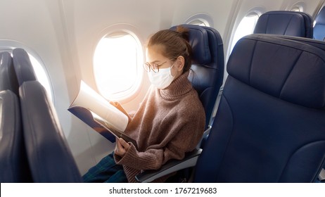 A Young Woman Wearing Face Mask Is Traveling On Airplane , New Normal Travel After Covid-19 Pandemic Concept 