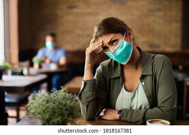 Young Woman Wearing A Face Mask And Feeling Worried About Something While Sitting In A Cafe, 