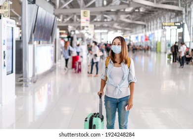 Young Woman Wearing A Face Mask And Holding A Mobile Phone Is Looking For A Check-in Counter At The Airport, New Normal Lifestyle Concept