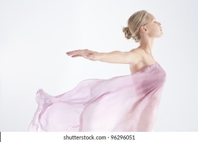 Young woman wearing a floating sarong with arms outstretched back.