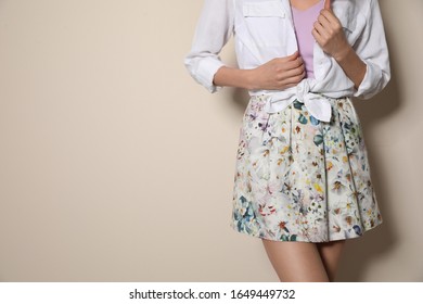 Young Woman Wearing Floral Print Skirt On Beige Background, Closeup. Space For Text