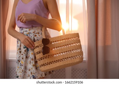 Young Woman Wearing Floral Print Skirt With Straw Bag Near Window At Home, Closeup