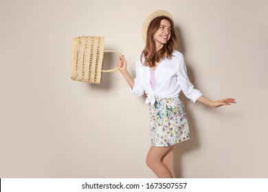 Young Woman Wearing Floral Print Skirt With Straw Bag On Beige Background