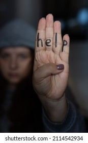 Young Woman Wearing Gray Hat Showing Four Fingers With Inscription On Hand Saying Help. Sign Of Domestic Violence. Physical, Mental, Psychological Abuse. Victim Of Beating And Under Pressure. 