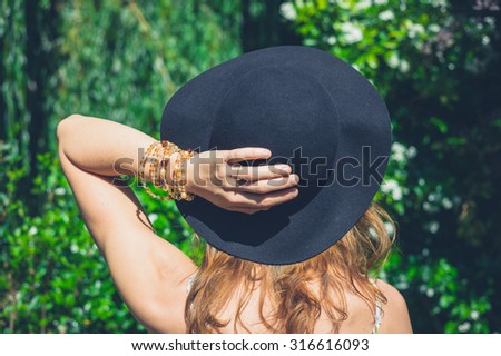 A young woman wearing a hat is walking in nature