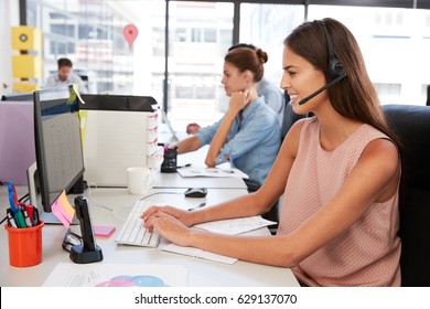 Young Woman Wearing Headset Using Laptop Computer In Office