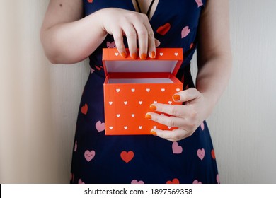 Young Woman Wearing Heart Printed Dress And Opening Small Box With Hearts On It