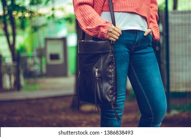 Young Woman Wearing Jeans And Pink Top Carrying An Over The Shoulder Leather Bag – Urban Looking Young Lady With A Stylish Outfit And A Purse Outdoors