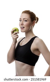 young woman wearing keep fit clothes eating an apple