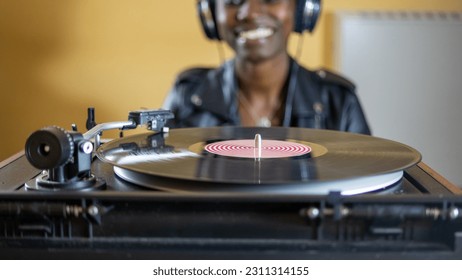 young woman wearing a leather jacket using headphones while playing a vinyl record on a vintage turntable - Shutterstock ID 2311314155