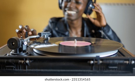 young woman wearing a leather jacket using headphones while playing a vinyl record on a vintage turntable - Shutterstock ID 2311314165