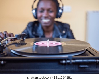 young woman wearing a leather jacket using headphones while playing a vinyl record on a vintage turntable - Shutterstock ID 2311314181