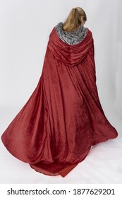 A Young Woman Wearing A Long Red Velvet Cloak Against A Plain Studio Backdrop