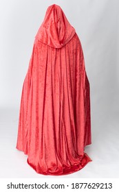 A Young Woman Wearing A Long Red Velvet Cloak Against A Plain Studio Backdrop