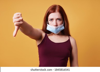 Young Woman Wearing Medical Face Mask Wrong Under Nose And Making Thumbs Down Gesture - Protest Against Corona Virus Covid Measures